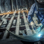 Worker welding large piece of metal.